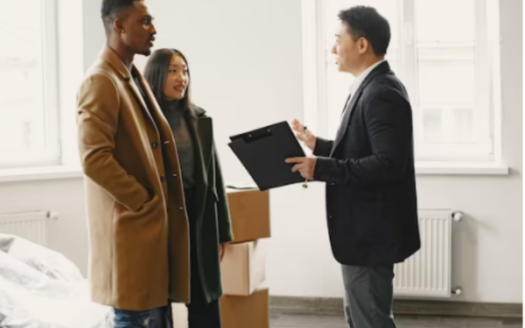 Young Couple, An Asian Woman And An African Man, Happily Signing Documents For Their New House Purchase.&Quot;