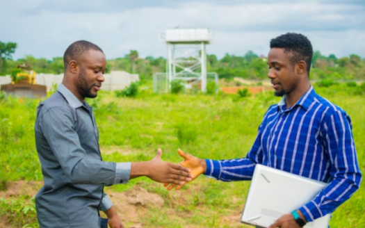 Two dynamic African entrepreneurs sealing a successful land banking deal in Nigeria with a firm handshake, symbolizing the promising opportunities in the real estate sector